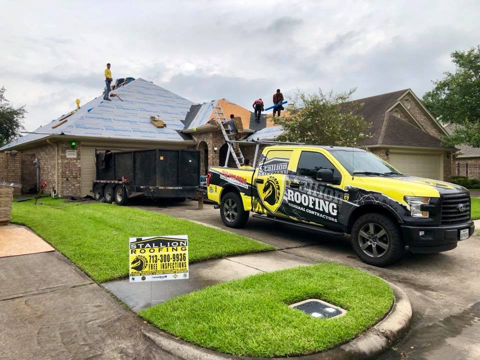 Stallion Roofing & Solar Solutions crew working on a roof and Stallion Roofing & Solar Solutions truck in driveway